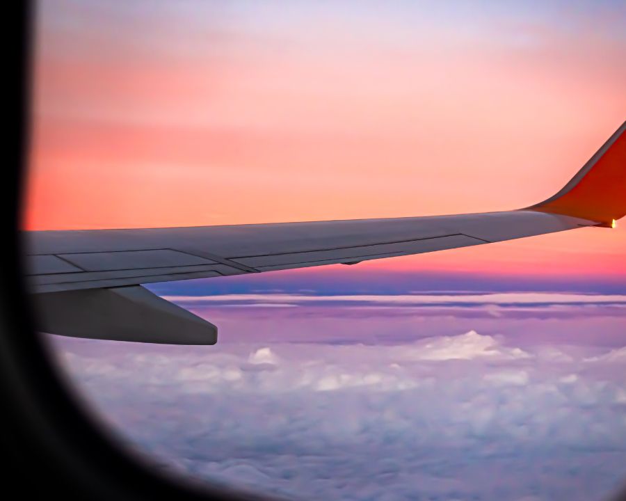 Plane wing over clouds at sunset — emigrating from the UK